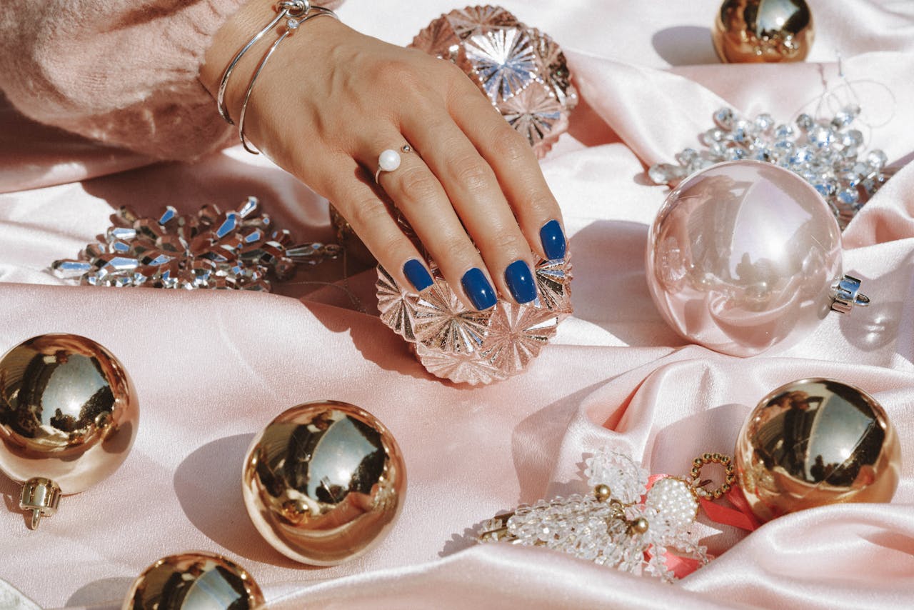 Person Wearing Gold Ring and Blue Manicure